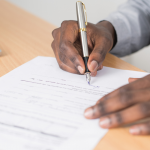 Closeup of person's hands signing paperwork